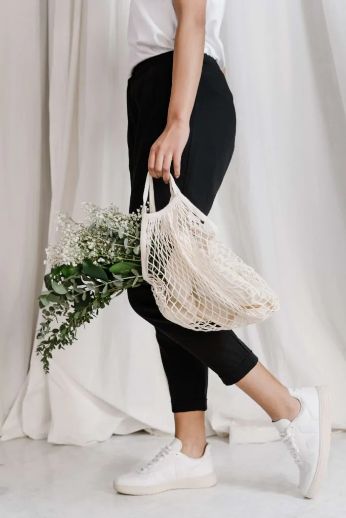 woman wearing sustainable clothing and carrying reusable tote bag