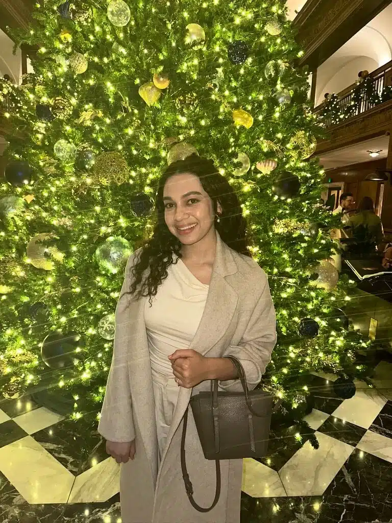 elegant woman wearing neutral one shoulder top and coat with mini tote