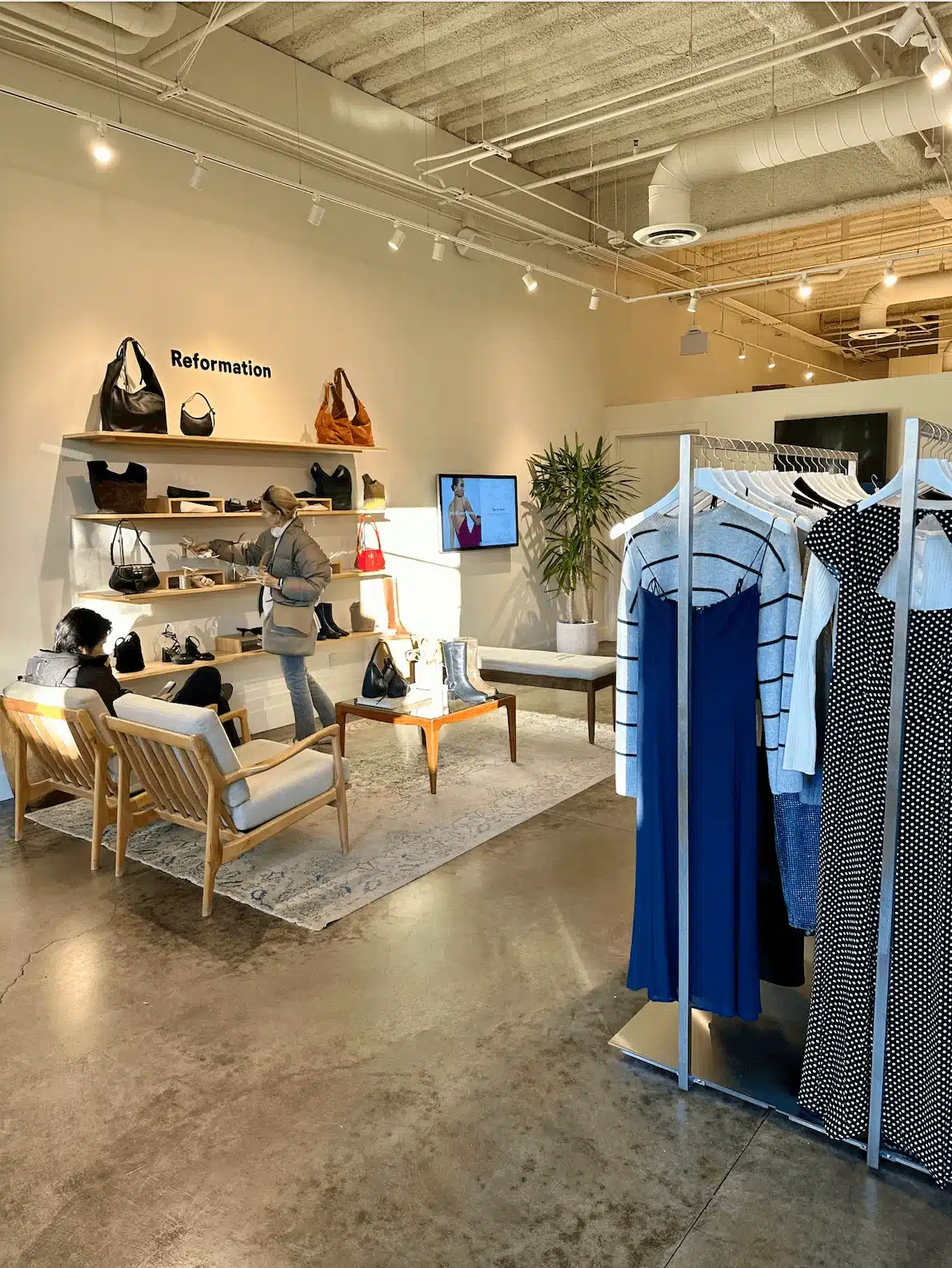 Reformation store with dresses on racks and purses on the wall