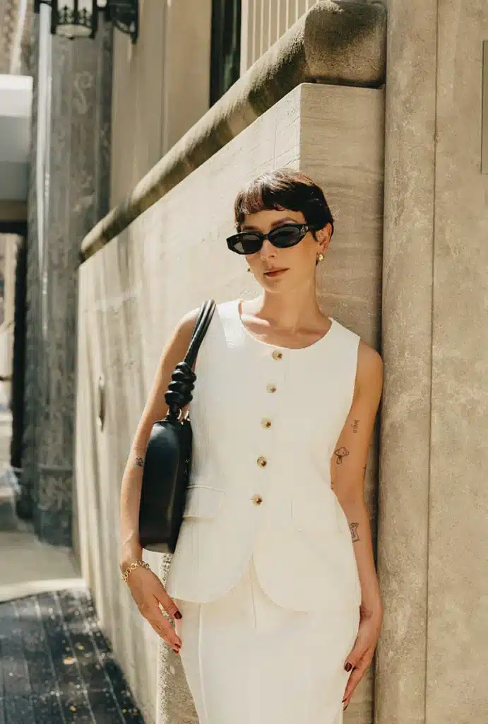 Chic woman in Ines Linen Vest and matching ivory skirt with black purse