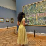 Woman looking at painting in Nuuly rented dress for nuuly vs BNTO review
