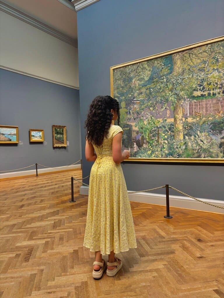 Woman looking at painting in Nuuly rented dress for nuuly vs BNTO review