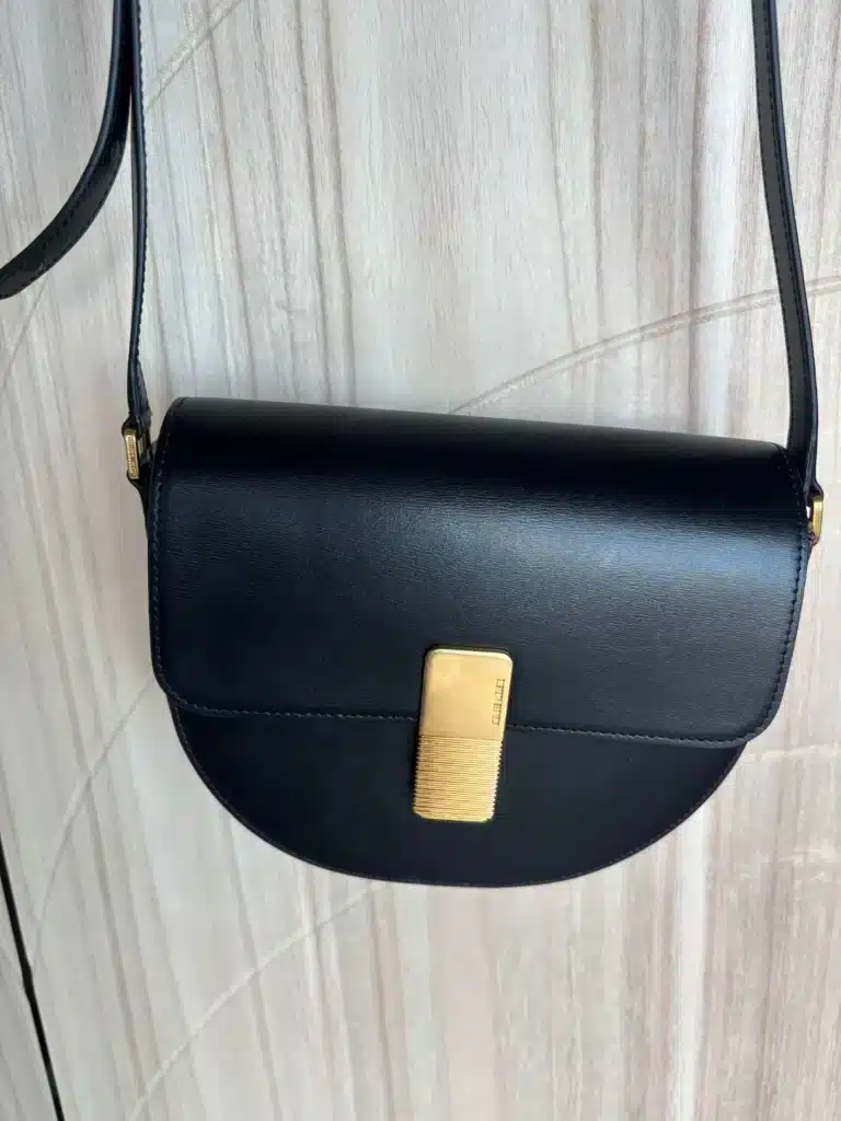 black leather bag hanging in front of wood panel